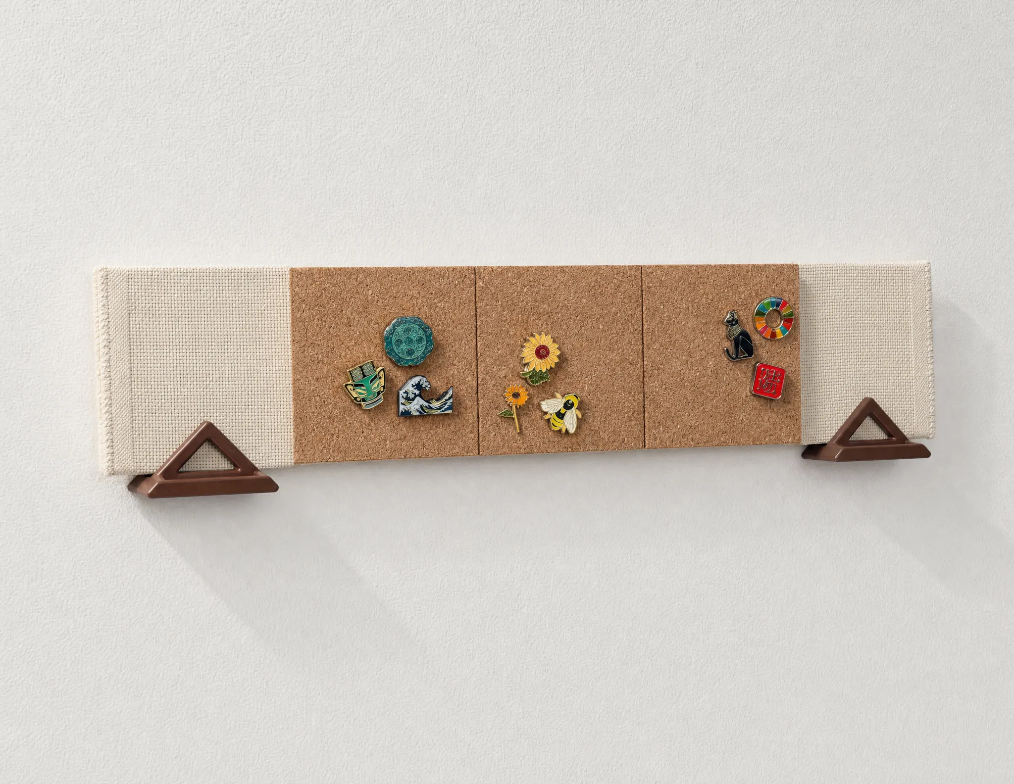 The Pinpal wall-mounted pin display, showing enamel pins arranged across its swappable backing scene.